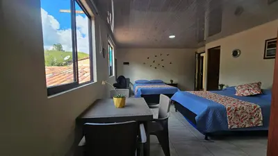 a room with two beds and a table and a window at Hospedaje Santa Teresita in Concepción