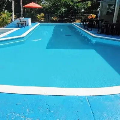 a blue swimming pool with a table and chairs at Beautiful duplex in Honda