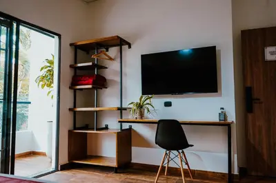 a room with a tv on a wall with a chair at Stadium Home Shelter in Medellín