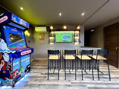 a bar with chairs and a video game machine at THE CAVE - Mancave, Pool & Arcade, by Lleras Park in Medellín