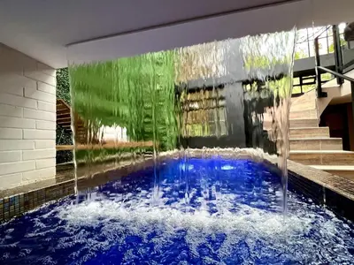 a swimming pool in a house with a water fountain at THE CAVE - Mancave, Pool & Arcade, by Lleras Park in Medellín