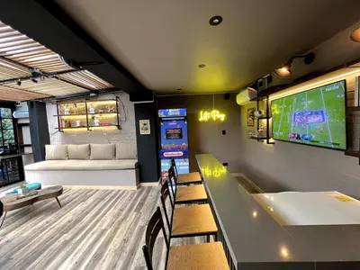 a room with a table and chairs and a large screen at THE CAVE - Mancave, Pool & Arcade, by Lleras Park in Medellín