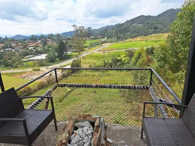 a balcony with two chairs and a view of a valley at Chalet las palmas Poblado in Medellín