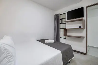 a bedroom with a white bed and a flat screen tv at TERRA - Heated Small Pool, BBQ & AC Lleras Park in Medellín