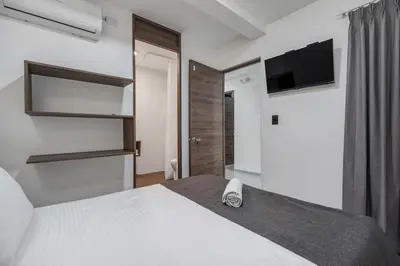 a bedroom with a white bed and a tv on the wall at TERRA - Heated Small Pool, BBQ & AC Lleras Park in Medellín