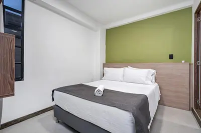 a bedroom with a large bed with a phone on it at TERRA - Heated Small Pool, BBQ & AC Lleras Park in Medellín