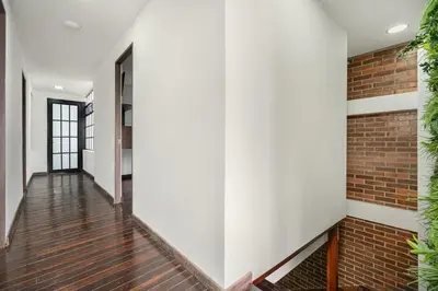 a hallway with white walls and a brick wall at ARYA - Huge Hot Tub & AC Steps from Lleras Park in Medellín