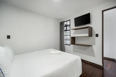 a white bedroom with a bed and a television at ARYA - Huge Hot Tub & AC Steps from Lleras Park in Medellín