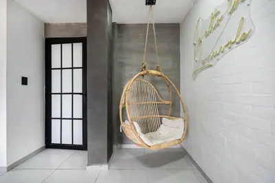 a hanging rattan chair in a room with a wall at ARYA - Huge Hot Tub & AC Steps from Lleras Park in Medellín