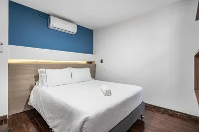 a bedroom with a white bed with a blue wall at ARYA - Huge Hot Tub & AC Steps from Lleras Park in Medellín