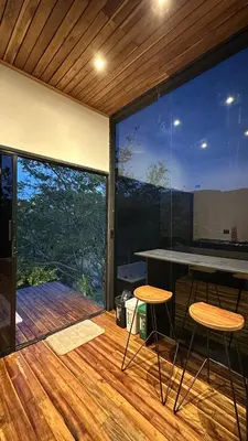 a room with a table and two stools on a deck at Cabaña 35min de Medellín, Benevento Reserva Botánica in Girardota