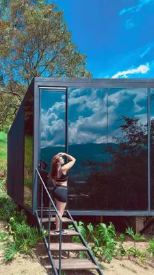 a woman is sitting on the stairs in a glass house at Cabaña 35min de Medellín, Benevento Reserva Botánica in Girardota