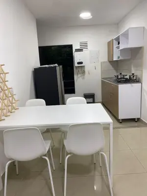 a kitchen with a white table and white chairs at Apartahotel Provenza in Medellín