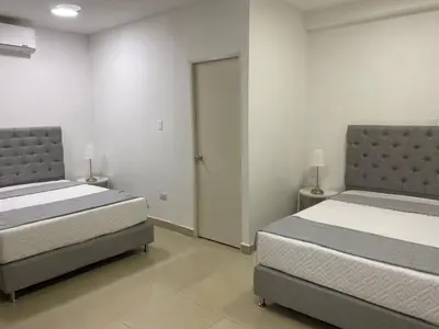 a bedroom with two beds and a door to a room at Apartahotel Provenza in Medellín