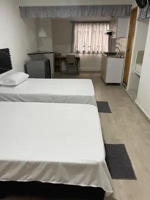 two white beds in a room with a table at Apartamento amoblado en Belén in Medellín