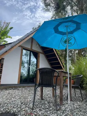 a blue umbrella sitting next to a table and a chair at Encanto Verde cabaña sencilla in Marinilla