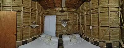 a room with two beds in a wooden room at Hostal Servus Pizzeria café in San Carlos