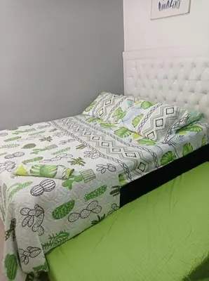 a bed with a green and white comforter on it at Apartasol Santafe de Antioquia in Santa Fe de Antioquia