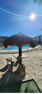 a straw umbrella on a beach with a bench at Apartasol Santafe de Antioquia in Santa Fe de Antioquia