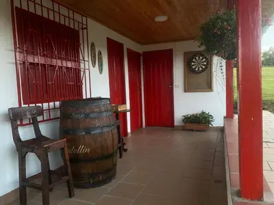 a room with a red door and a chair and a barrel at Valle Sereno, Hospedaje rural cerca del Salto del Buey in Abejorral
