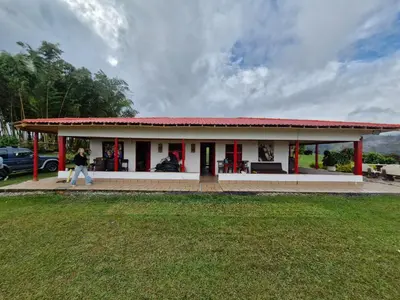a woman walks in front of a small building at Valle Sereno, Hospedaje rural cerca del Salto del Buey in Abejorral