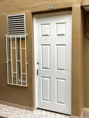 a white door with a window next to a building at Apartaestudio Medellin - Santa Lucia in Medellín