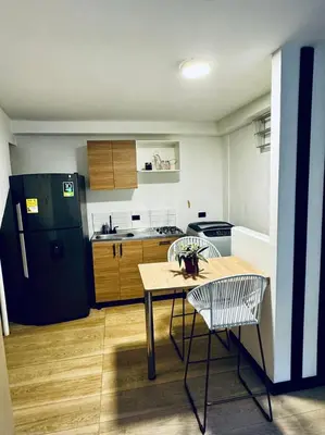 a kitchen with a table and chairs and a refrigerator at Apartaestudio Medellin - Santa Lucia in Medellín