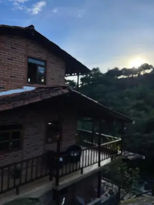 a house with a balcony with the sunset in the background at Finca Acogedora con Área de BBQ, Parking Privado y Hamacas in Guarne