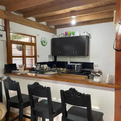 a kitchen with a counter with chairs and a stove at Finca Acogedora con Área de BBQ, Parking Privado y Hamacas in Guarne