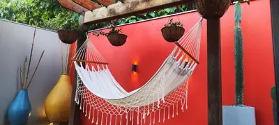 a hammock hanging from a building with a red wall at Glamping Raíces in Manizales