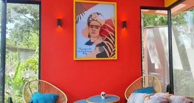 a red wall with two tables and a picture at Glamping Raíces in Manizales