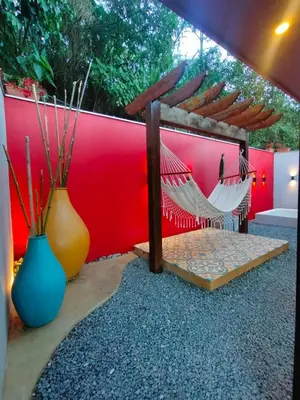 a hammock and two vases sitting next to a red wall at Glamping Raíces in Manizales