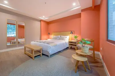 a bedroom with orange walls and a bed and tables at Modern Comfort in El Tesoro Medellín 301 in Medellín