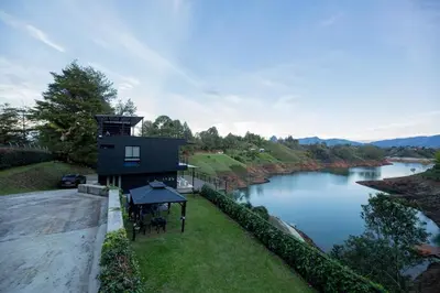 a house on a hill next to a river at Beautiful cabin Guatapé vista-acceso al lago in La Pradera