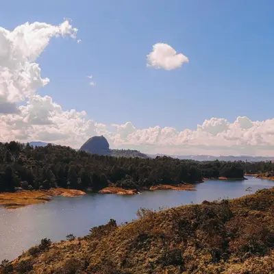 a river in the middle of a field with trees at EL NiDO HOTEL GUATAPE in Guatapé