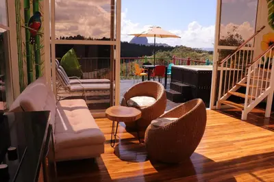 a living room with chairs and a balcony with a piano at EL NiDO HOTEL GUATAPE in Guatapé