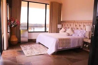 a bedroom with a large bed and a large window at EL NiDO HOTEL GUATAPE in Guatapé