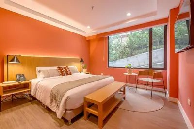 a bedroom with orange walls and a bed and a window at Elegant Stay Steps from El Tesoro Mall 304 in Medellín