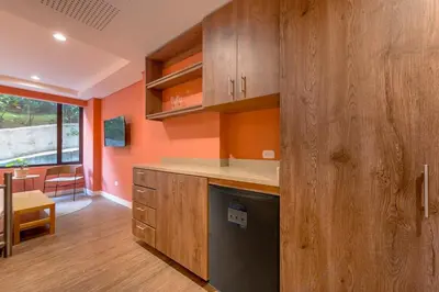 a kitchen with orange walls and a black dishwasher at Elegant Stay Steps from El Tesoro Mall 304 in Medellín