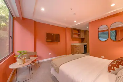 a bedroom with orange walls and a bed and a table at Elegant Stay Steps from El Tesoro Mall 304 in Medellín