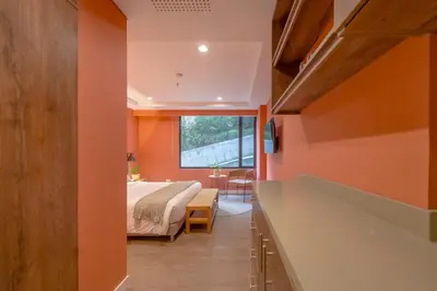 a bedroom with orange walls and a bed and a window at Elegant Stay Steps from El Tesoro Mall 304 in Medellín