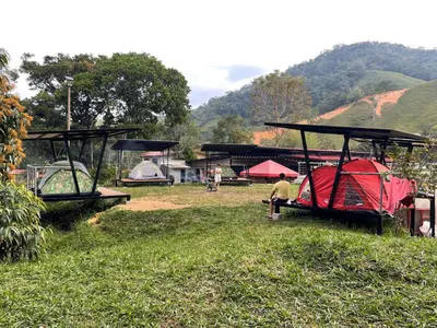 a group of tents in a field with a man sitting in the grass at Camping bajo techo y con estilo in San Rafael