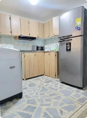 a kitchen with a stainless steel refrigerator and wooden cabinets at exclusive apartment in laureles Estadio in Medellín
