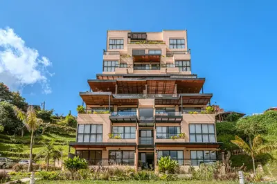 a tall building on a hill with palm trees at Villa reservoir view in Guatapé