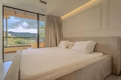 a bedroom with a large bed with a large window at Villa reservoir view in Guatapé