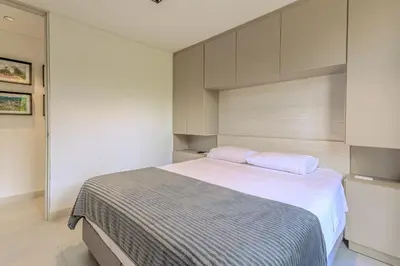 a bedroom with a bed with white sheets and pink pillows at Villa reservoir view in Guatapé