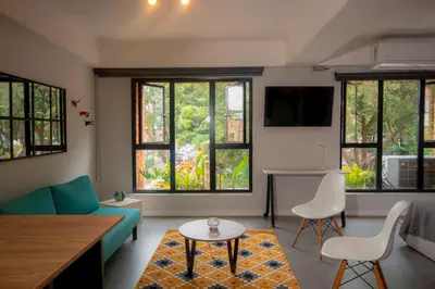 a living room with a couch and chairs and windows at Céntrico Apartaestudio en el Parque de Poblado in Medellín