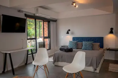 a bedroom with a bed and two white chairs at Céntrico Apartaestudio en el Parque de Poblado in Medellín