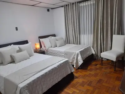 a hotel room with two beds and a chair at Modern, Comfortable, Spacious & Central in Manizales
