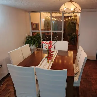 a dining room table with white chairs and a table with flowers at Modern, Comfortable, Spacious & Central in Manizales